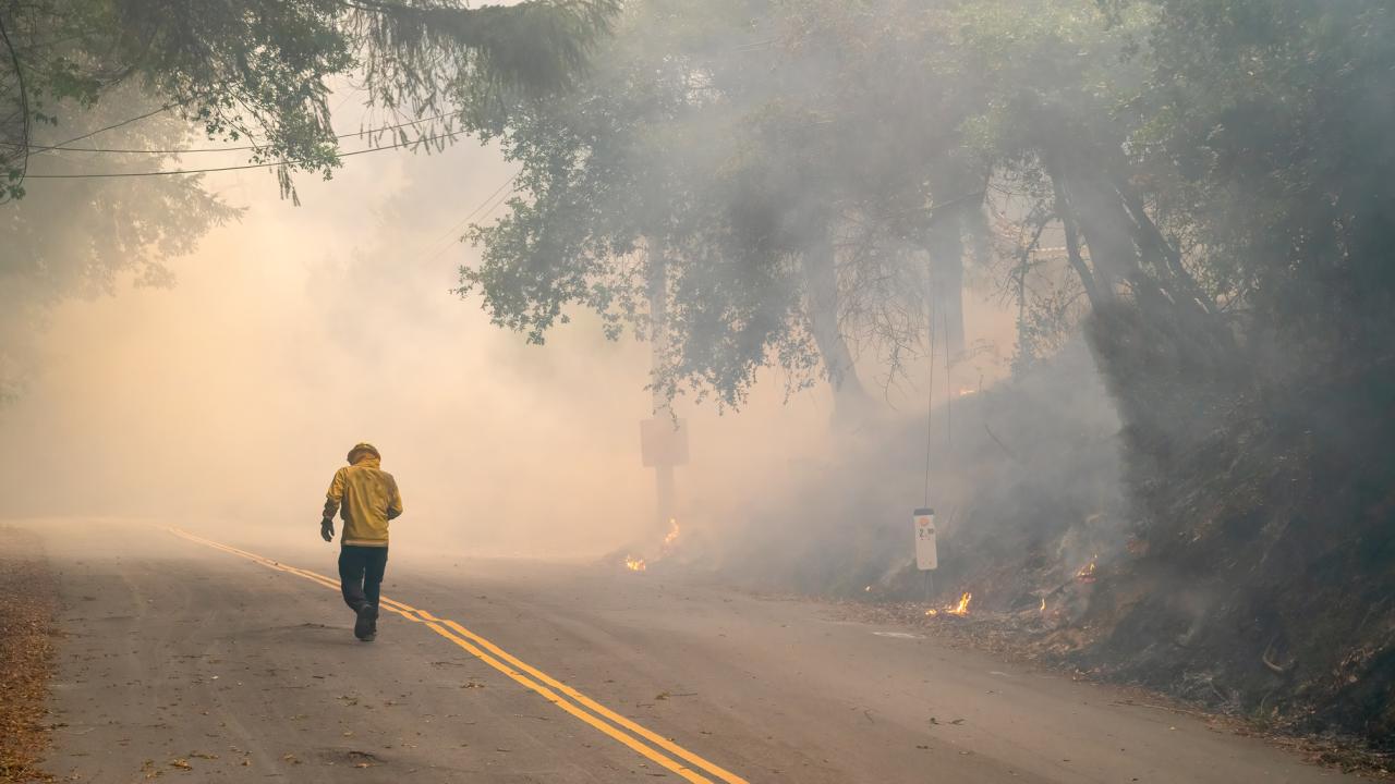 Firefighter walking into wildfire smoke
