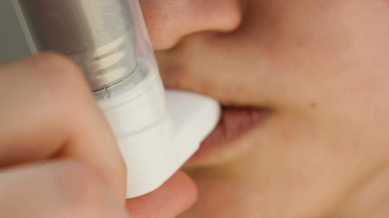 Teen with asthma using an inhaler