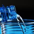 Water pouring into glass from plastic bottle