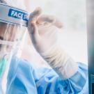 Image of healthcare worker with a face shield and mask, looking exhausted 